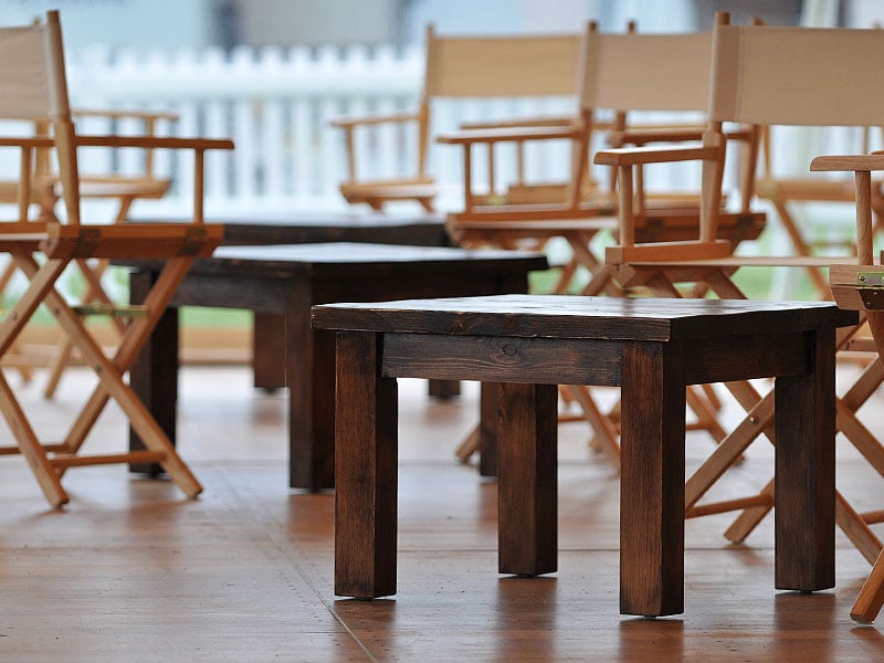 Low dark wooden tables surrounded by light wooden director-style chairs with cream canvas seats and backs.