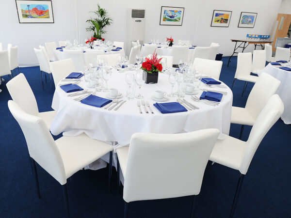 rio chairs with round banqueting tables covered with white table cloth and laid with cutlery, chinaware and glassware