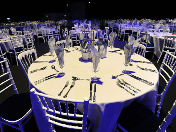 white linen tablecloths on round dining event banquet tables with chiavari chairs