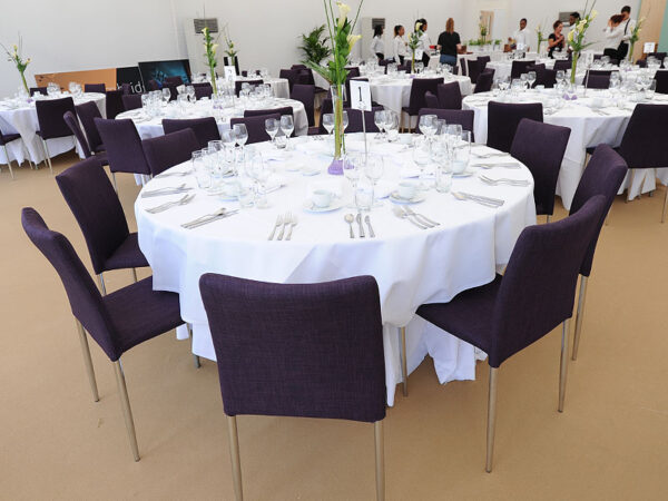 white linen tablecloths on round dining event banquet tables with purple rio chairs