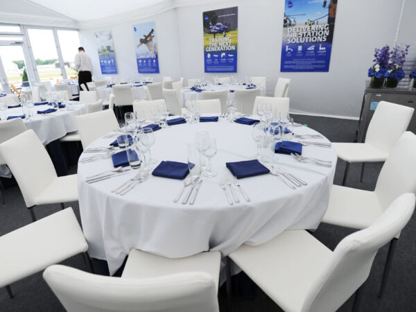 white linen tablecloths on round dining event banquet tables with white rio chairs