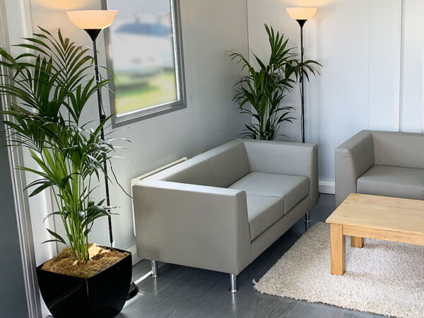 grey infiniti two seater sofas with palm plants and uplighters