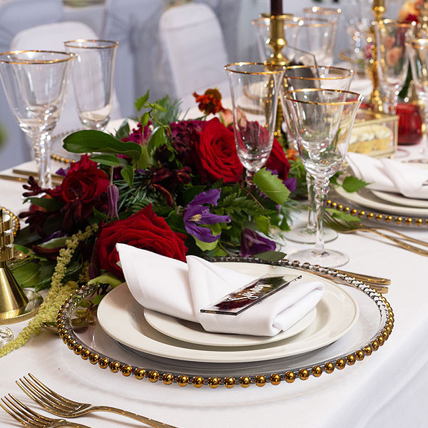 gold rimmed glassware, gold allure cutlery and gold beaded glass plates on a floral wedding table